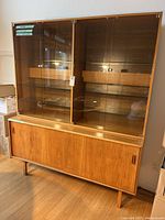 Full view of two-piece teak cabinet showing glass hutch and lower storage base