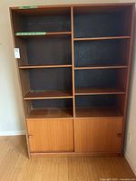 Front view of Domino Møbler teak bookcase showing open shelves and lower sliding doors