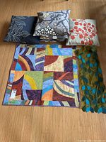 Group shot of four cushions, quilt wall hanging, felted scarf