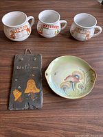 Group shot of three soup mugs, slate welcome plaque, and mushroom plate