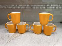 Front view of six yellow Corning mugs stacked