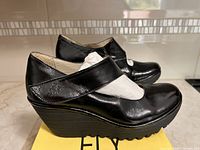 Fly London Luxor black leather Mary Jane wedge shoes on box showing both shoes side profile