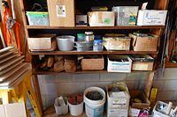 Shelving with multiple boxes and bins of nails, screws, spikes, tool belt visible