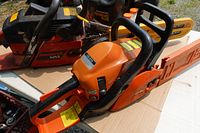 Two gas chainsaws and oil containers on tabletop