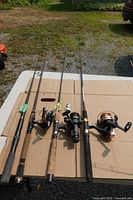Four fishing rods with three reels displayed on table