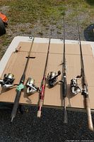 Four fishing rod and reel combos laid out on table