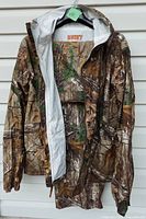 Front view of camo rain jacket hung on hanger