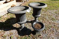 Two large urn planters and one small urn planter on gravel surface