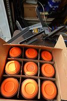 Launcher atop table with box of orange clay targets opened showing partitions