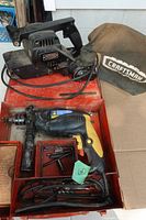 Overall view showing both tools: belt sander with dust bag and hammer drill in metal tray