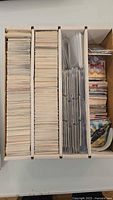 Top view of three-row storage box filled with trading cards and plastic binder pages
