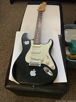 Full view of Academy black electric guitar on white background