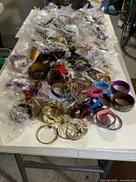 wide view of entire table loaded with assorted costume jewelry pieces, many in plastic bags