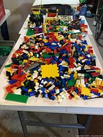 Wide shot of table filled with loose LEGO bricks and partial builds