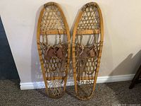 Full view of pair of wooden snowshoes leaning against wall