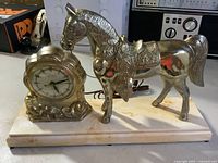 Front view showing gold-tone horse figure and clock on marble base