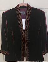 Front view of burgundy velvet jacket showing embroidery and tag