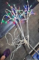 Three white lighted branch trees with wiring visible