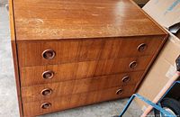 Front view of teak veneer dresser showing four drawers with circular pulls