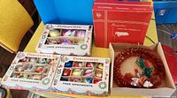 Overall lot: three boxes of ornaments, red Dominion light box, red cellophane wreath, replacement candle