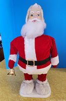Full view of standing mechanical Santa on base holding bell