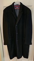 Full view of black cashmere overcoat on hanger