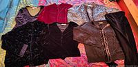 Seven velvet garments laid out showing variety of colors and styles