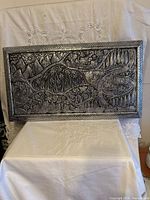 Full view of embossed metal wall art on stand