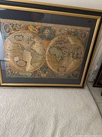 Front view of framed double-hemisphere map print in gold-tone frame