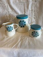 front view of teapot, creamer and sugar bowl showing pattern and lids