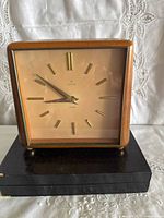 Front view of Junghans Exacta wood square table clock on black base