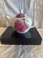Front view of Maxwell & Williams Lilac Rose teapot on black stand