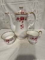 Front view of teapot, sugar bowl and creamer showing pattern and shape