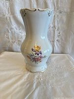 Front view of white porcelain vase with floral bouquet and gold trim