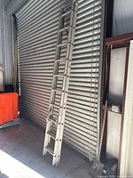 Full view of the aluminum extension ladder leaning against a roll-up door
