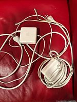 Both Apple MagSafe adapters with cables on red surface