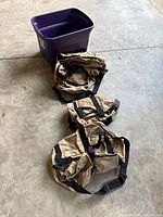 Overhead view of three tan duffel bags and purple tote