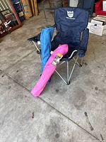 Open navy folding camp chair with blue and pink carry-bagged chairs leaning