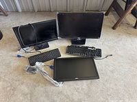 Group shot of three monitors, two keyboards, and assorted cables