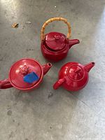 Three red glazed ceramic pieces on floor