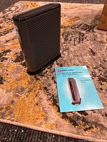 Modem standing on carpet next to quick start guide