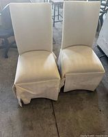 Front view of both ivory skirted Parsons chairs showing overall design and condition