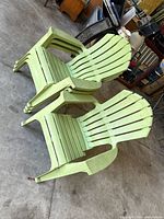 Two light green plastic resin Adirondack chairs on concrete floor