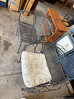 Full view of both wrought iron chairs, one with cushion