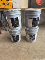Four Sherwin-Williams Cashmere 5-gallon paint buckets stacked