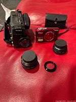 Group shot of camcorder, digital camera, two lenses, adapter ring, case