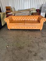 Full front view of tan leather Chesterfield sofa