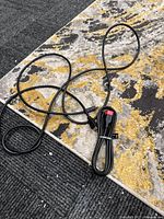 Coiled HDMI cable with red caps and loose cable on patterned rug