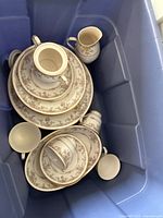 Mixed plates, cups and small pitchers in storage tote