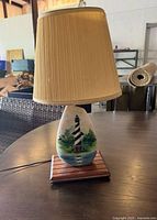 Front view of lamp showing lighthouse artwork, wooden base, shade
